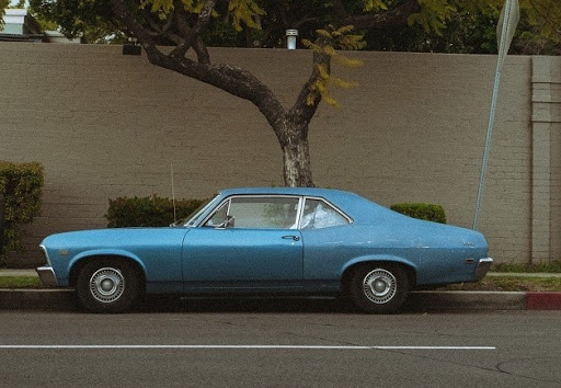 A vintage blue car parked under the tree